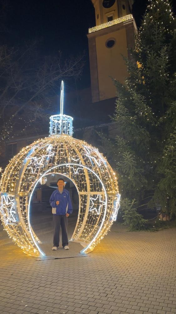 privat ein junger Mann steht in einer übergroßen hell erleuchteten Weihnachtskugel