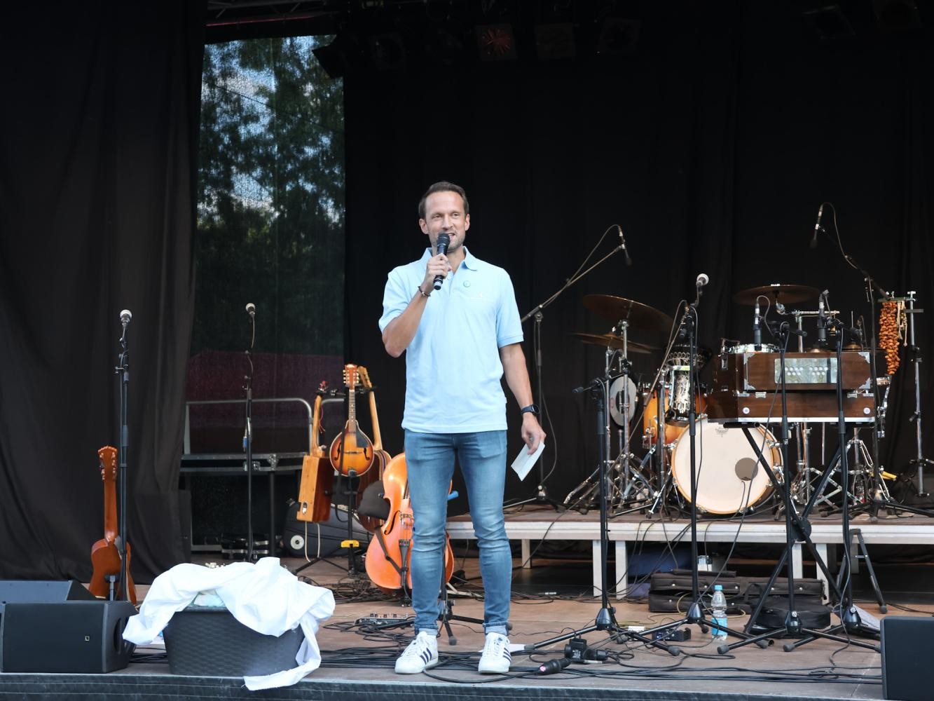 Ein Mann steht mit Mikrofon auf einer Bühne.