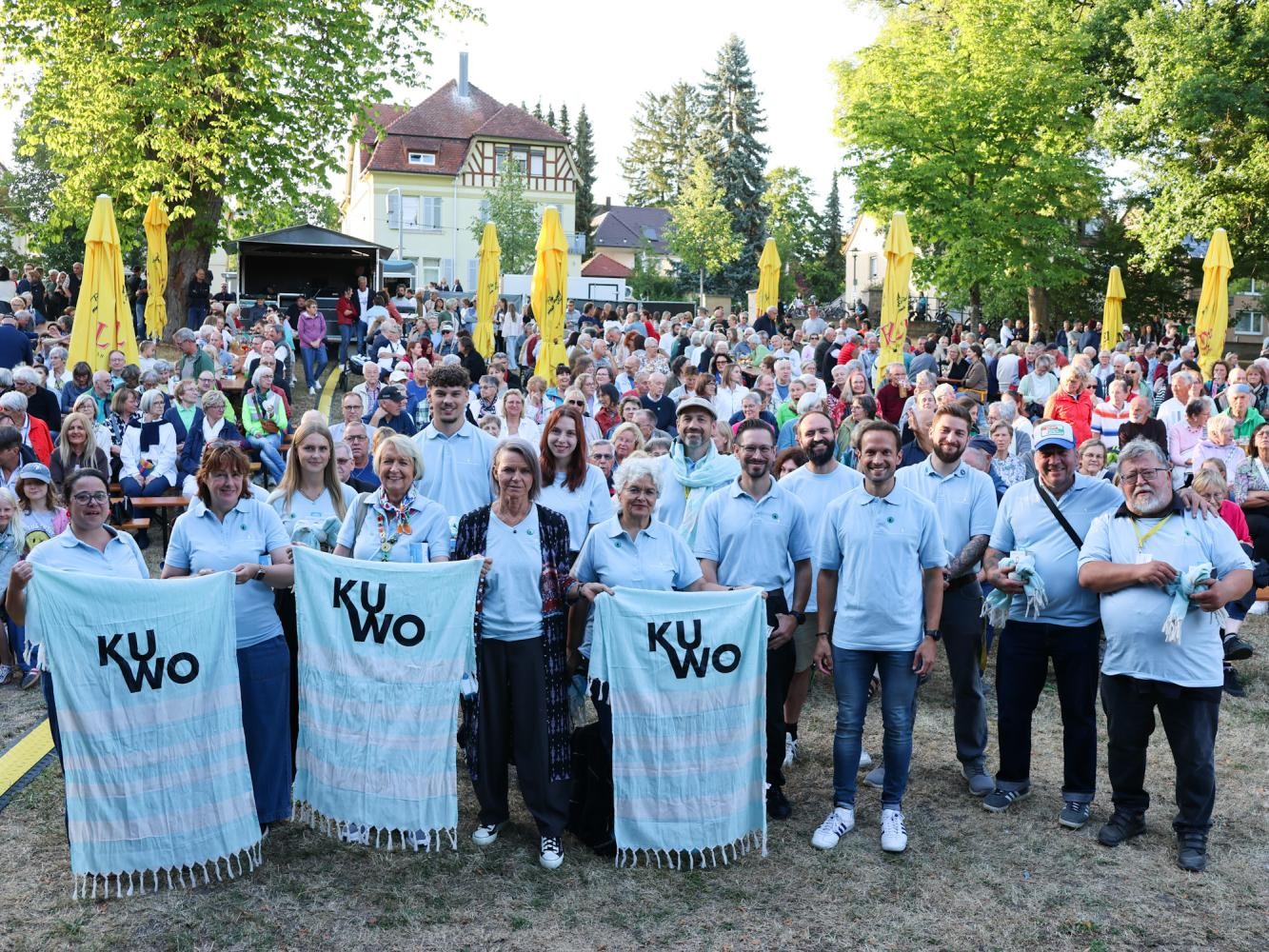 Eine Gruppe mit gleichen Shirts und Handtüchern steht vor einem Publikum