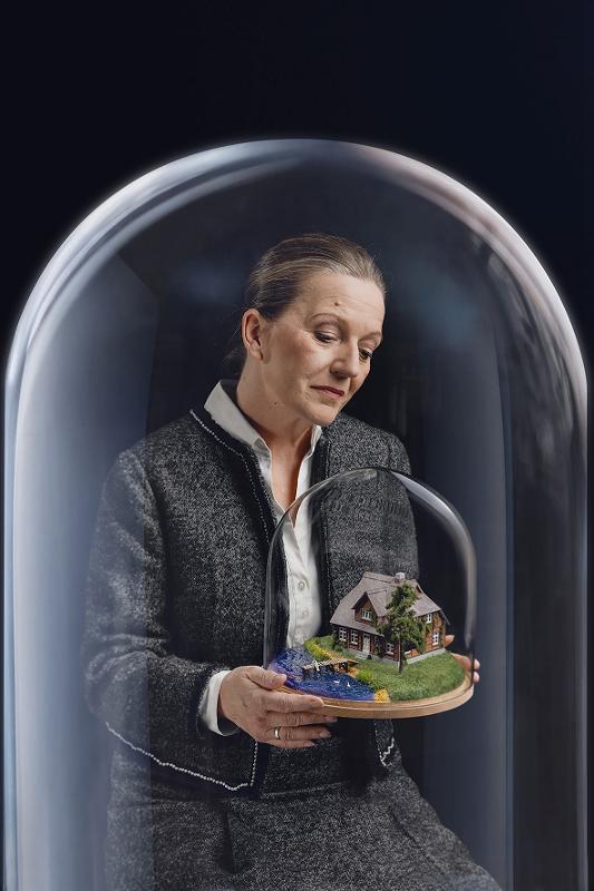Bild von einer Frau die eine Glaskugel mit einem Haus darin in der Hand hält