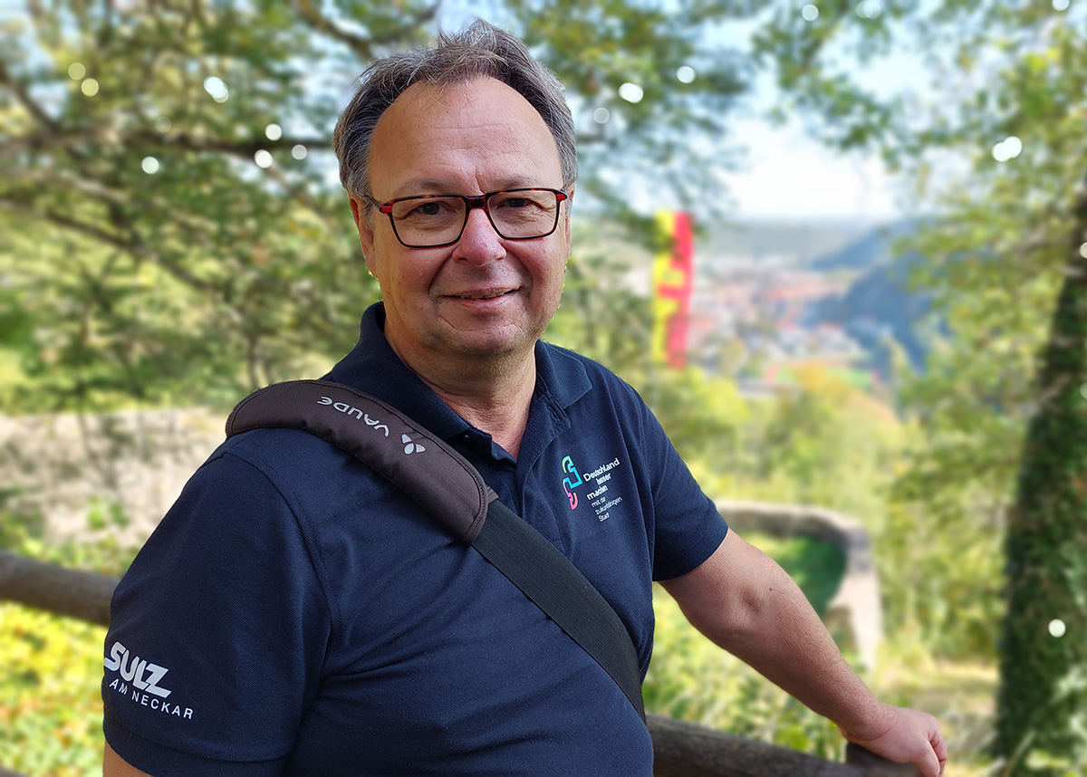 Ein Mann mit Brille und Tasche über der Schulter sieht in die Kamera