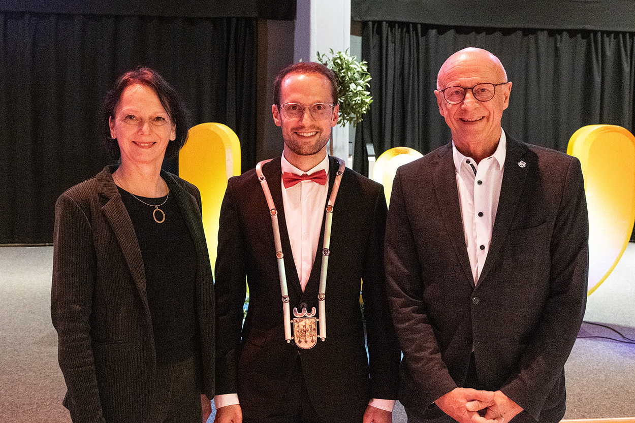 eien Frau und zwei Männer lächeln in die Kamera