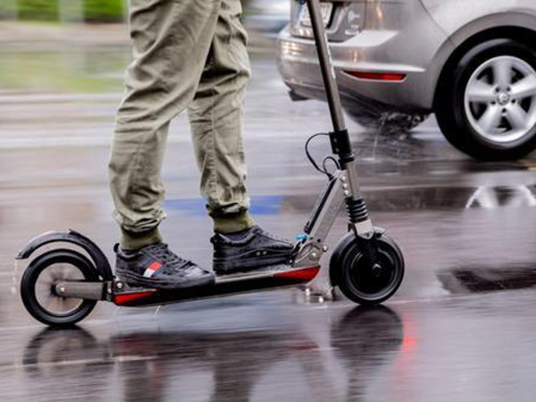 Eine Person auf einem E-Scooter fährt auf einer Straße
