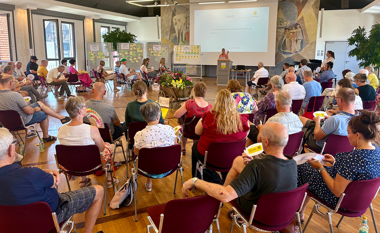 Viele Menschen sitzen in einem Saal zusammen