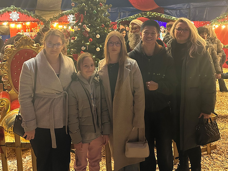 eine augenscheinliche Familie steht auf einem hell erleuchteten Weihnachtsmarkt für ein Foto bereit