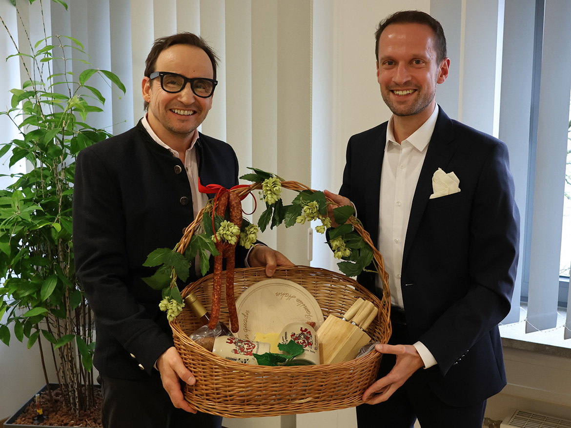 Zwei Männer halten lächelnd einen Präsentkorb