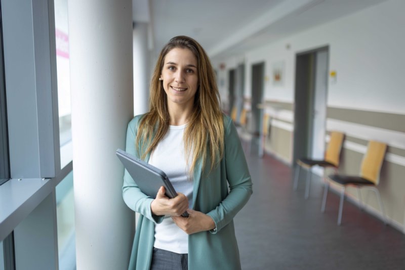 Frau lehnt an einer Säule mit einem IPad in der Hand