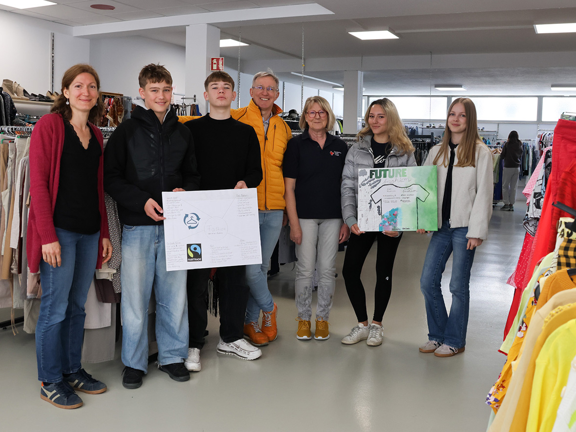 Einige Personen stehen in einem Kleiderladen, teilweise mit Plakaten in der Hand