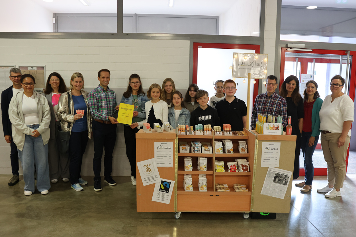 Einige Erwachsene und Kinder stehen neben und hinter einem Verkaufsstand und lächeln in die Kamera