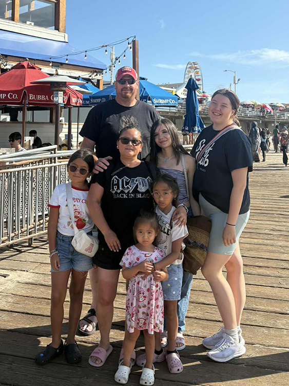 Eine kleine Gruppe steht lachend bei sonnigem Wetter unter einem Torbogen