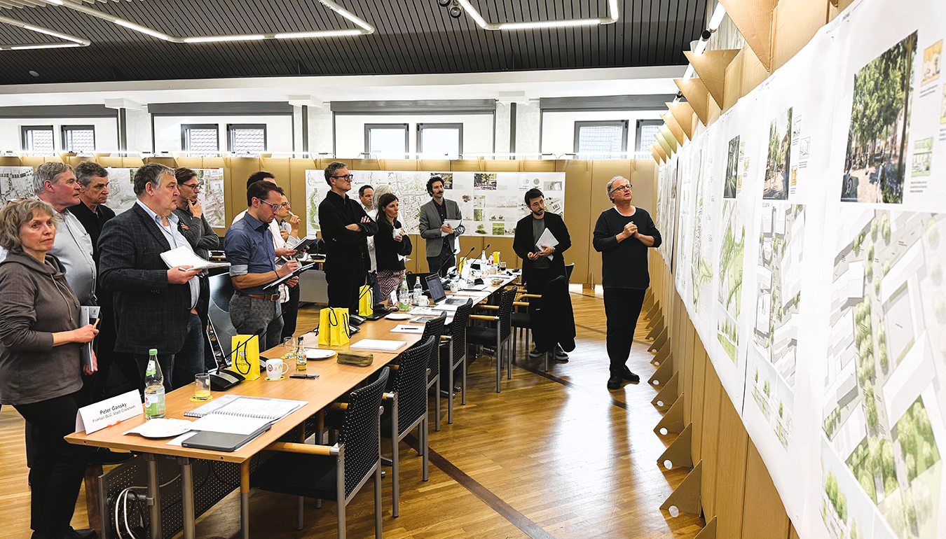 Einige Menschen stehen hinter einer Tischreihe vor Plakatwänden