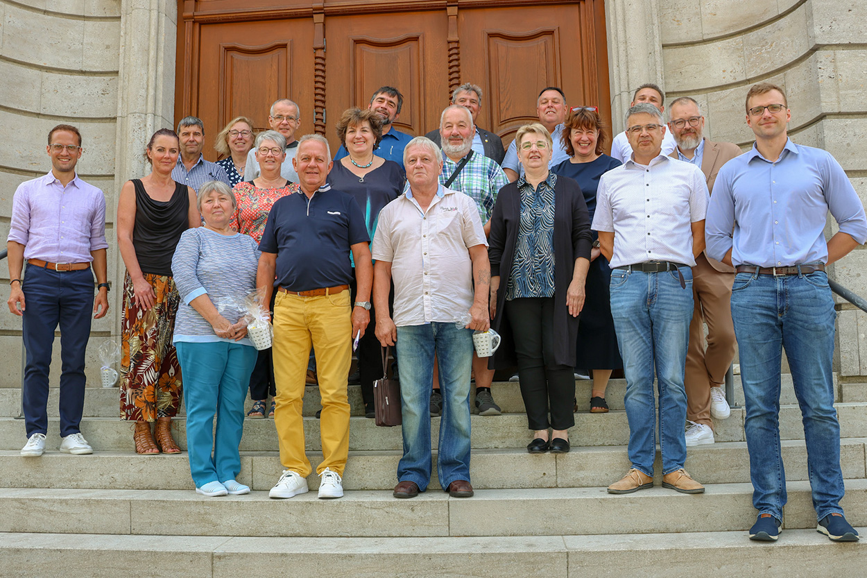 Einige Menschen stehen vor einem Tor auf einer Treppe und lächeln in die Kamera.