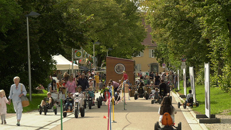 Viele Kinder mit Spielgeräten auf einer Straße