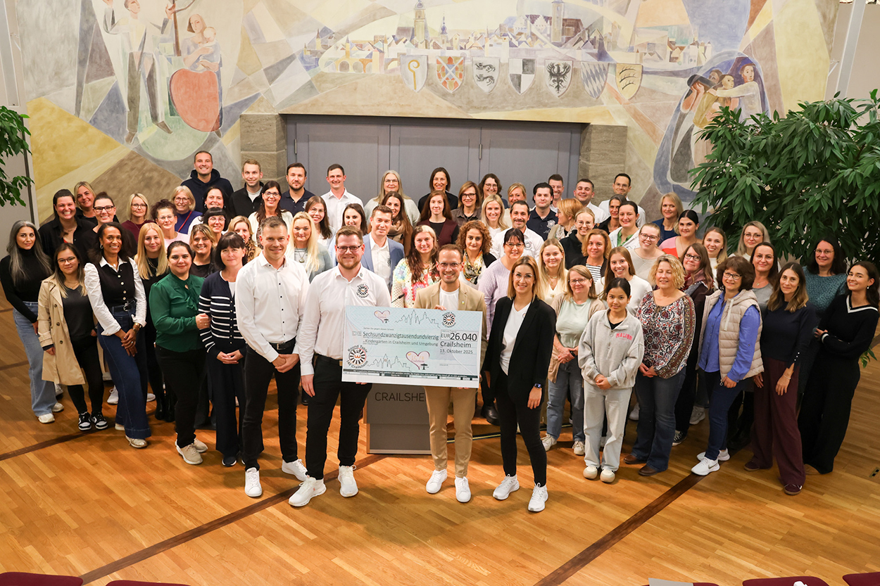 Stadtverwaltung Eine große Gruppen Menschen steht in einem Saal zusammen und blickt in die Kamera, vier Personen vorne mit einem Symbolscheck