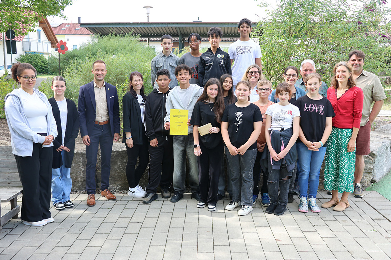 Einige Schülerinnen und Schüler lächeln mit Erwachsenen in die Kamera