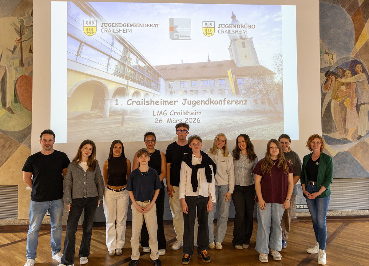 Eine Gruppe Jugendlicher steht vor einer Leinwand für ein Foto bereit