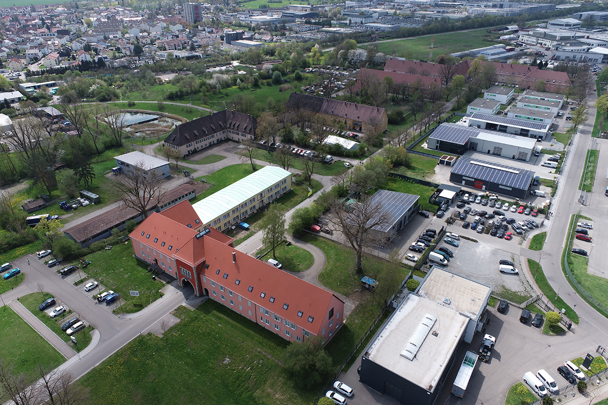 einige Gebäude, teils mit Photovoltaik auf dem Dach, aus der Vogelperspektive