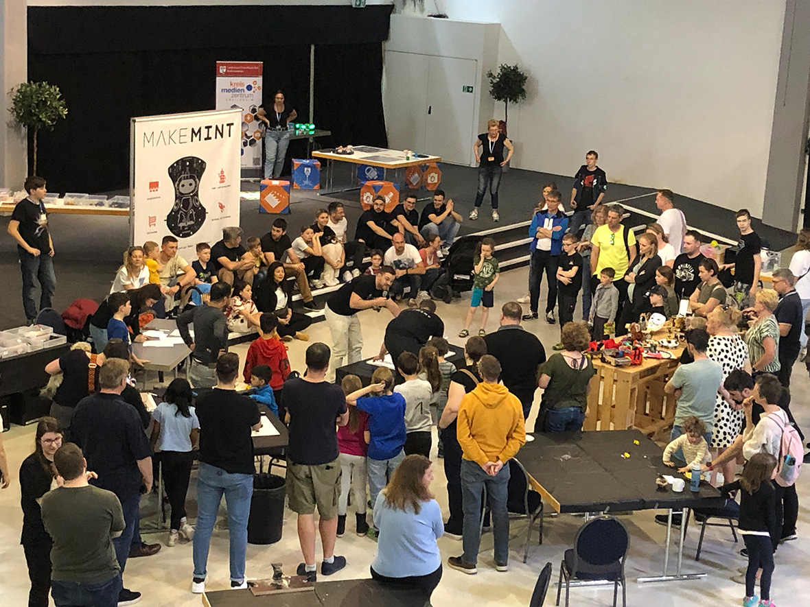 viele Menschen um Tische in einer Halle