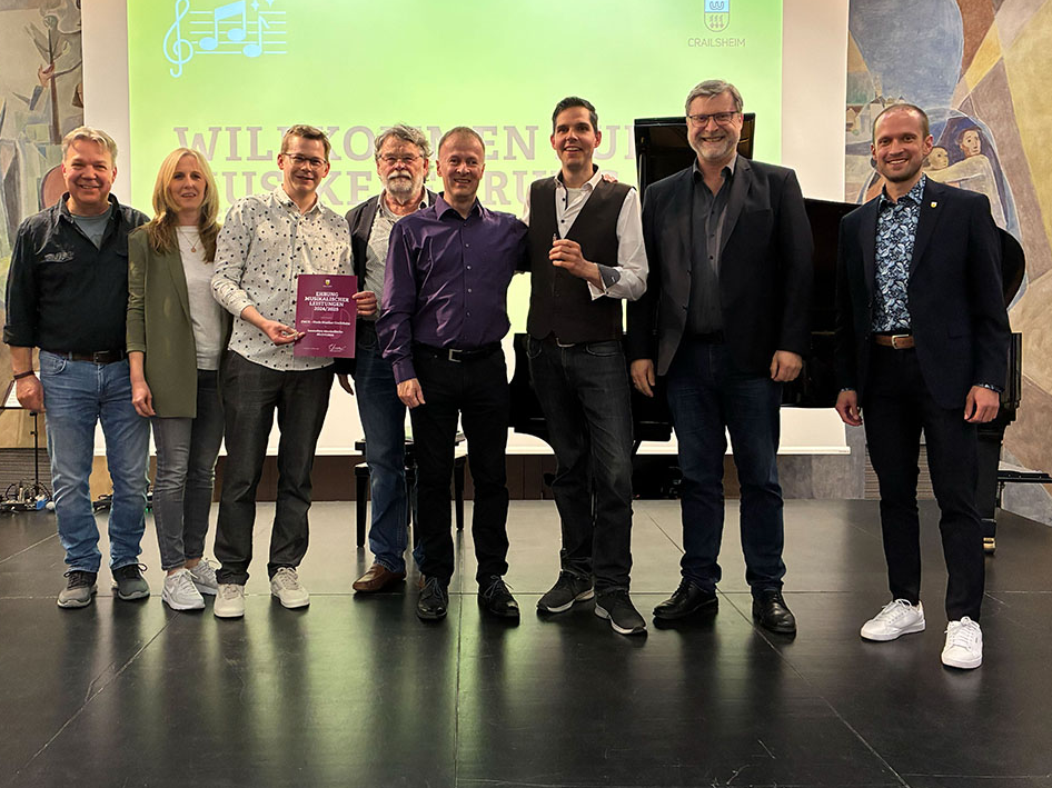 Eine Gruppe Menschen lächelt auf einer Bühne in die Kamera