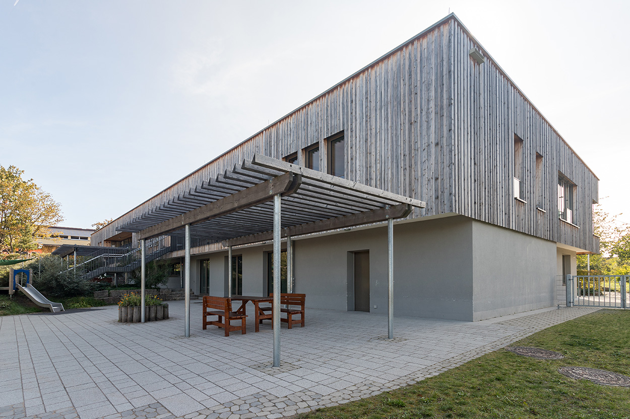Stadtverwaltung Ein gepflastereter Hof vor einem Haus mit Holz verkeldiet und einer Überdachung