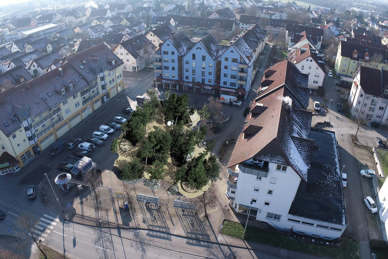 Ein Platz, um den sich mehrstöckige Häuser sammeln, auf dem digital ein kleiner Wald eingefügt ist