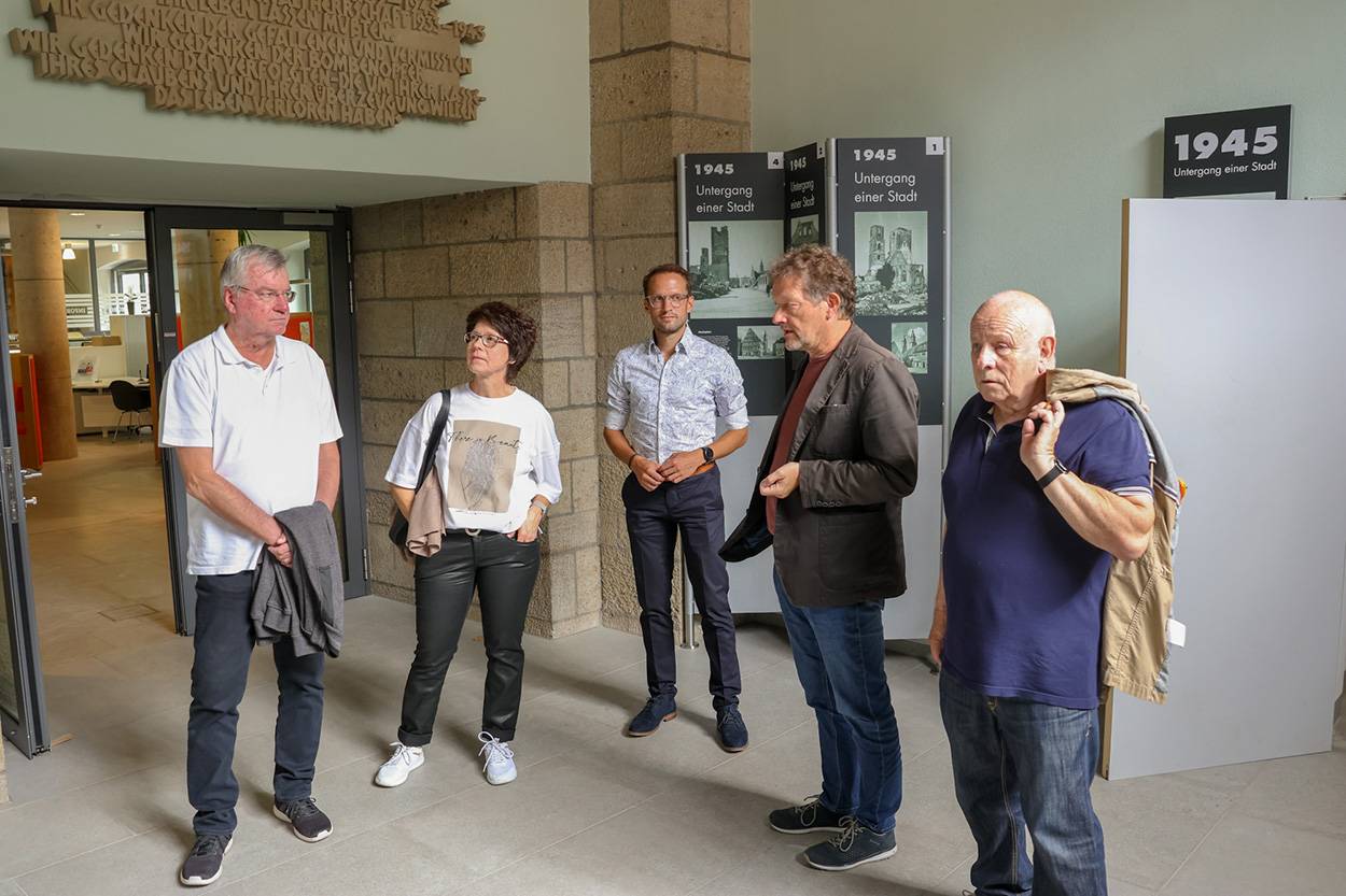 Fünf Personen stehen in einem Raum mit Stellwänden