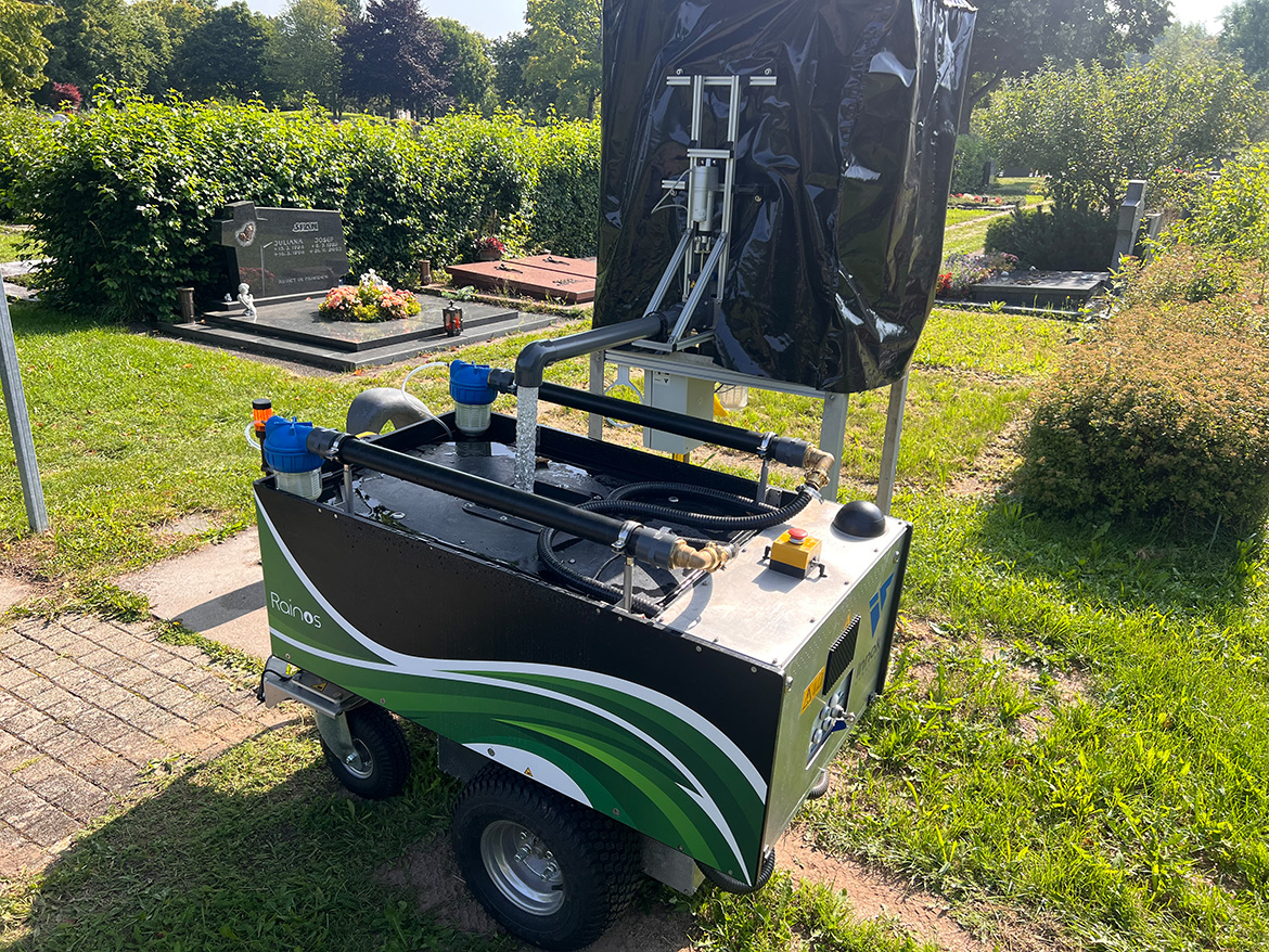 Ein großes Gefährt steht vor einem Kasten, aus dessen Hahn Wasser in einen Tank läuft