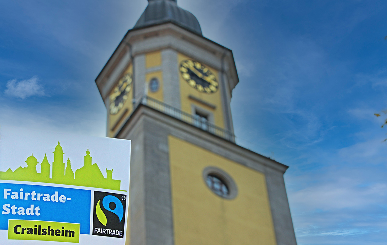 Ein Schriftzug ind er linken Bildecke "Fairtrade-Stadt Crailsheim" vor einem Turm