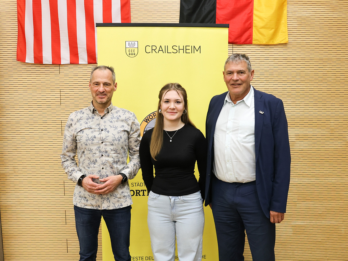 Zwei Männer und ein Mädchen lächeln in die Kamera.