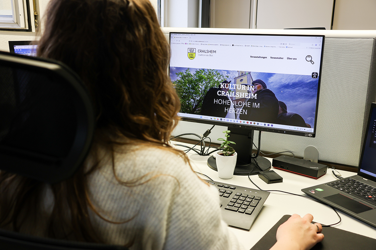 eine Frau sitzt vor einem PC-Bildschirm