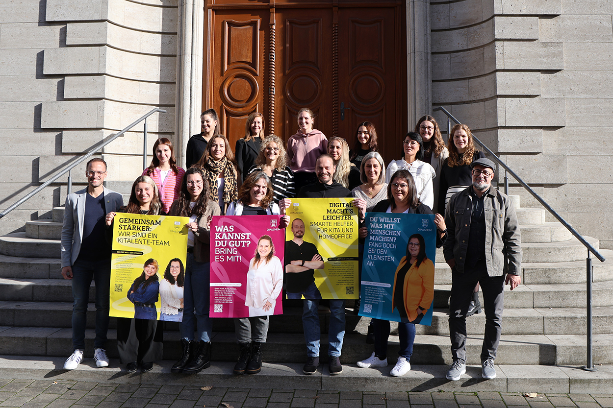 Einige Menschen mit Plakaten stehen auf einer Treppe und lächeln in die Kamera